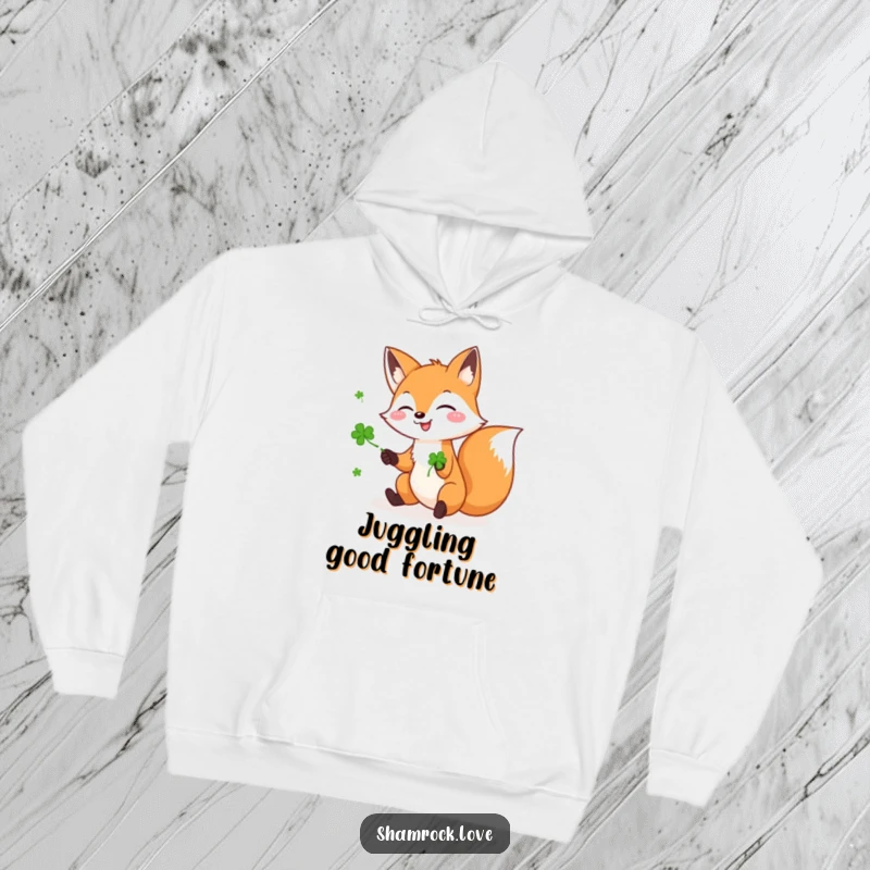 Funny hoodie featuring a playful fox juggling green shamrocks with glee, offering warmth and a touch of Irish luck.